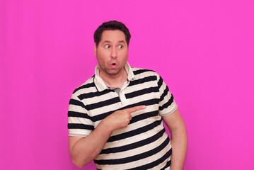 Caucasian man wearing casual striped t-shirt standing over isolated hot pink background shows...