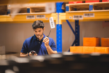 Male dispatcher, warehouse worker checking packages while using walkie-talkie in distribution warehouse storage. - obrazy, fototapety, plakaty