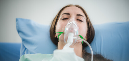 young woman patient receiving oxygen mask lying on a hospital bed, concept of medical and patient