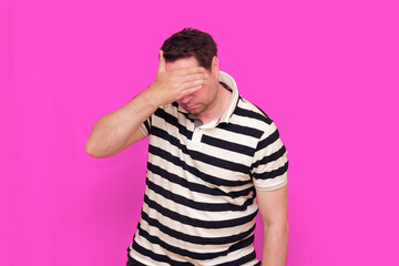 Caucasian man wearing casual striped t-shirt standing over isolated hot pink background shows...