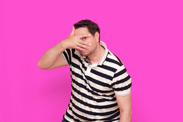 Caucasian man wearing casual striped t-shirt standing over isolated hot pink background shows various gestures.