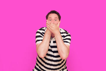 Caucasian man wearing casual striped t-shirt standing over isolated hot pink background shows...
