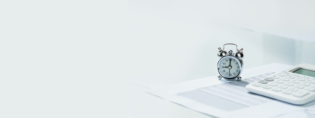 Alarmclock with calculator on financial paperwork. Finance and business concept blue banner....
