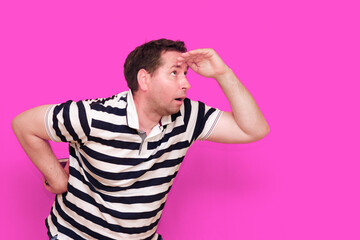 Caucasian man wearing casual striped t-shirt standing over isolated hot pink background shows...
