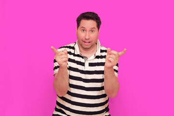 Caucasian man wearing casual striped t-shirt standing over isolated hot pink background shows...