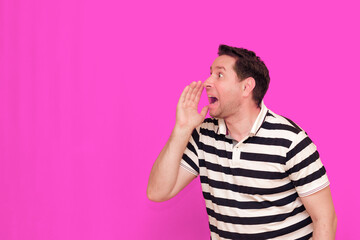 Caucasian man wearing casual striped t-shirt standing over isolated hot pink background shows...
