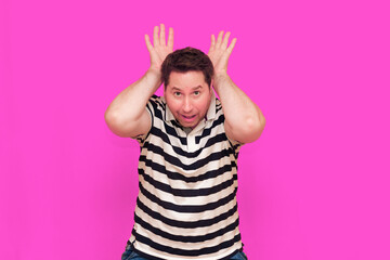 Caucasian man wearing casual striped t-shirt standing over isolated hot pink background shows...