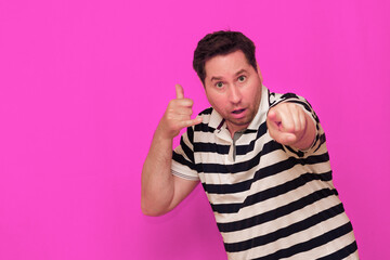 Caucasian man wearing casual striped t-shirt standing over isolated hot pink background shows...