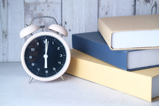 Stack Of Books And Clock On Table Close Up 