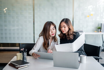 Two young asian businesswoman talking and working together at office.