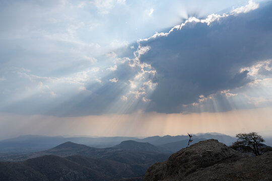 One man running downhill on a rock under a cloudy sky with sunrays