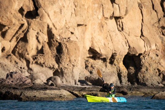 One woman paddling on a seat on top kayak close to the shore of Carmen Island in Loreto, Baja California, Mexico.