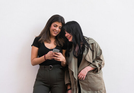 Two young women are using a smartphone on a white background