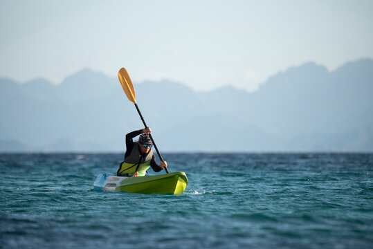 One woman paddling on a seat on top kayak close to the shore of Carmen Island in Loreto, Baja California, Mexico.