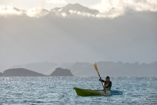 One woman paddling on a seat on top kayak close to the shore of Carmen Island in Loreto, Baja California, Mexico.