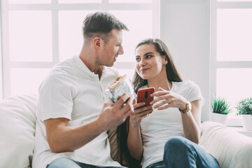 young couple with a smartphone sitting on a comfortable sofa.