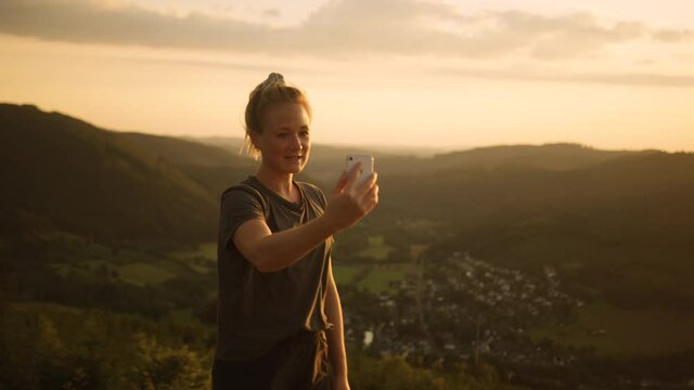 Outdoor Influencer creating instagram story on top of mountain for social media