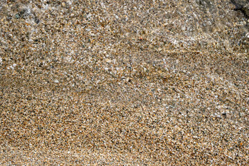 Fototapeta na wymiar Small pebbles and sand seabed background texture under clear shallow sea water, top view.