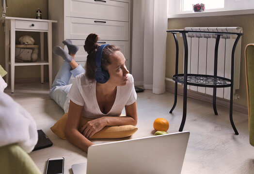 Young woman lying at the window at home with laptop