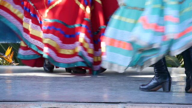 Latino women in colourful traditional dresses dancing Jarabe tapatio, mexican national folk hat dance. Street performance of female hispanic ballet in multi colored ethnic skirts. Girls in costumes.