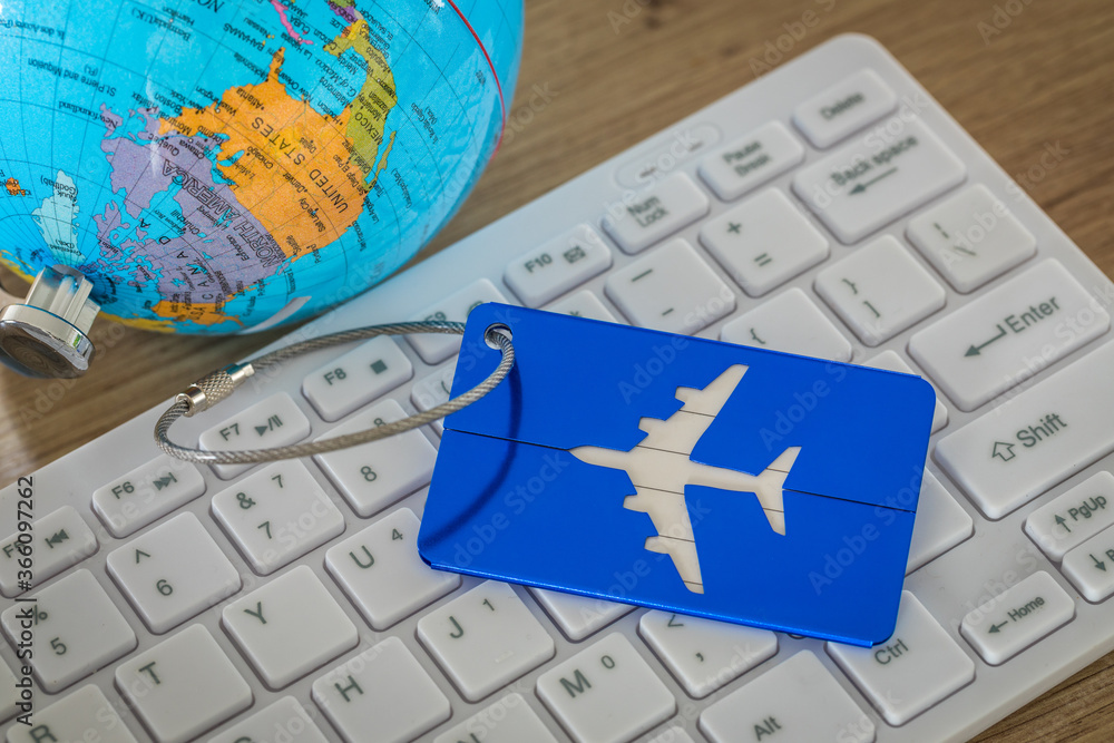 Fototapete globe with a baggage hanger and computer keyboard, concept for traveling around the world