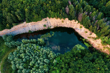 Blue lake at an old quarry surrounded by green forest 