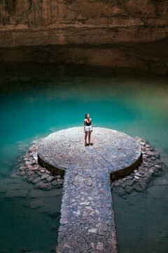 Girl in a cave with a blue cenote lake on the Yucatan