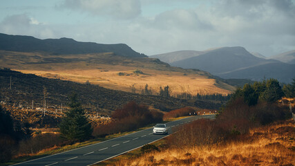car driving along road surrounded by hills