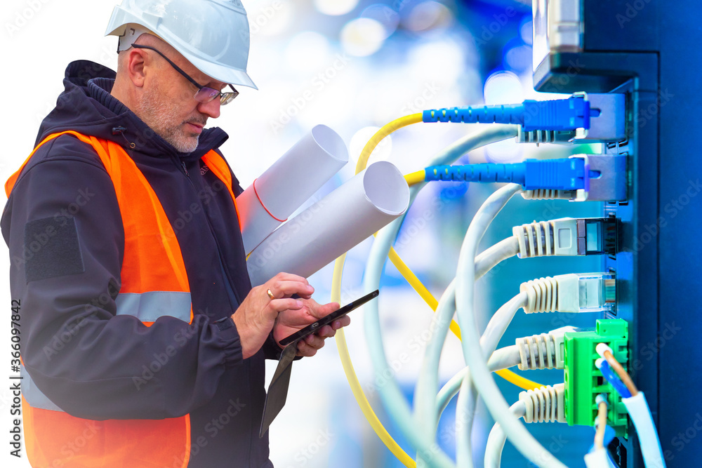 Poster man sets up a local network. worker next to network equipment. system administrator in a helmet. man