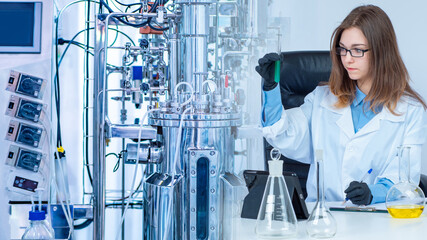 Microbiologist next to the bioreactor. Doctor biologist conducts experiments. Female laboratory...