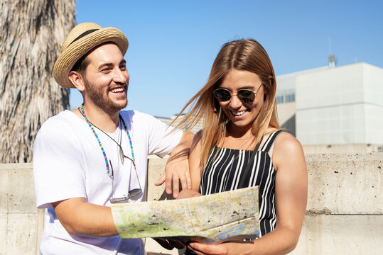 Happy tourist couple checking a city map outdoors in a sunny day