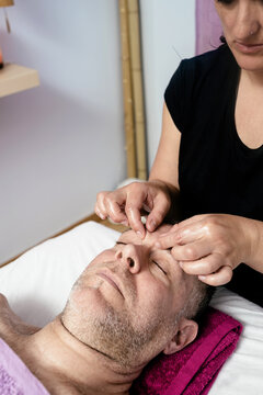 Female masseuse massaging a male patient's eyebrows