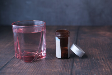 close up of pill contianer and glass of water on table 