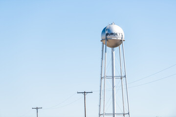 Burdett, USA view of water tower sign on street for city in Kansas countryside industrial town against sky