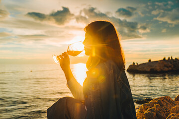woman drink wine at sea beach looking on sunset