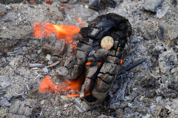Russian coin in fire on red-hot coal among the ashes. One rubles in fire. Russian currency...