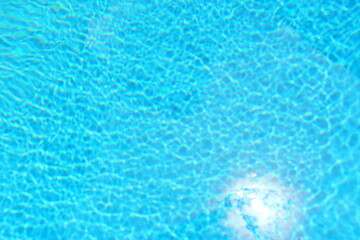 Naklejka na ściany i meble Blue water in the pool in summer. Relaxation and rest. The sun's rays are reflected in the water.