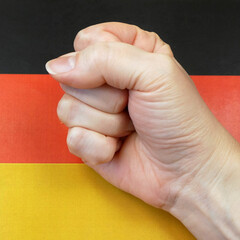 clenched fist against the background of the flag in germany, protests in germany concept