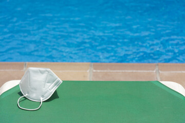 Mask on deckchair next to a swimming pool