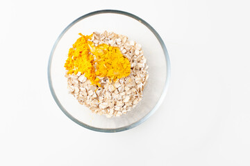Turmeric in a bowl with oatmeal and honey on a white background