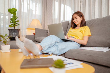 Woman sitting at a sofa working in computer at home on vacation.
