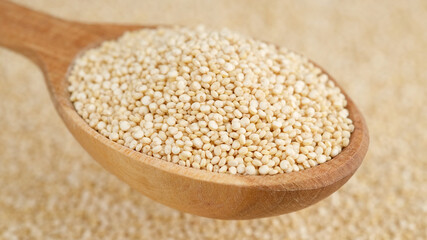 quinoa seeds in wooden spoon and on background. top view