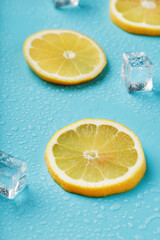 Slices of fresh lemon on a blue background with ice.