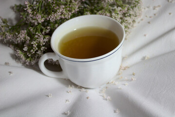 Baldriantee und Baldrianblüten auf einem Kopfkissen