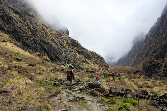Trekkers with a guide traversing a valley on the Himalayan Annapurna Base Camp trek route