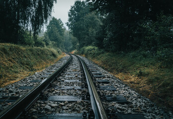 Narrow gauge rail track in forest on rain weather. Czech republic