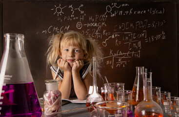 Curious little girl with test tubes and colorful substances with hands to her face makes tests at school laboratory. Small kid conducts science experiment on biology lesson. Biology education concept.