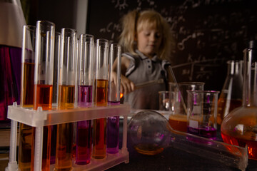  Curious little girl with test tubes and colorful substances makes tests at school laboratory. Small kid learning chemistry .Selective focus.