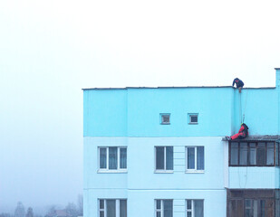 Workers alpinists repair the roof of a panel house at a height. Dangerous job, industrial