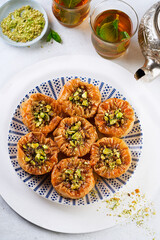 Middle eastern baklava with honey, pistachios, mint tea on a light background, selective focus. Ramadan, Eid concept. Top view.